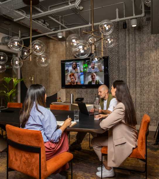 A team hybrid working in a meeting room with a large screen