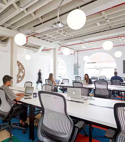 Open plan workspace with long tables and scattered people